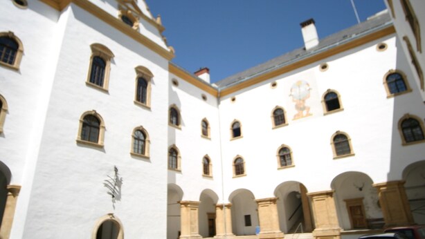 Ein weißes Gebäude mit zahlreichen Rundbogenfenstern und einem zentralen Innenhof.