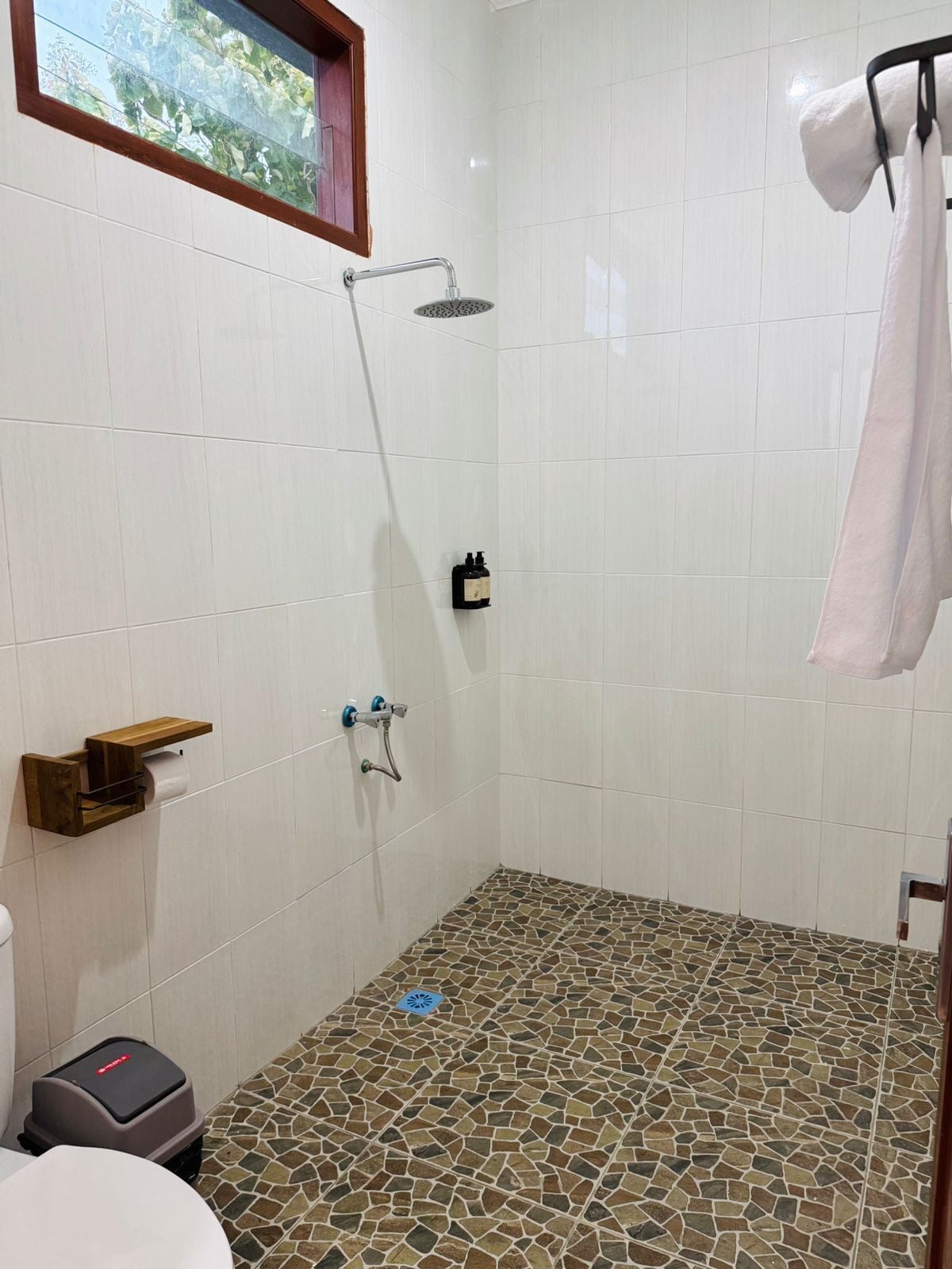 Un baño pequeño con paredes de azulejos, suelo de mosaico, toallero y un inodoro.