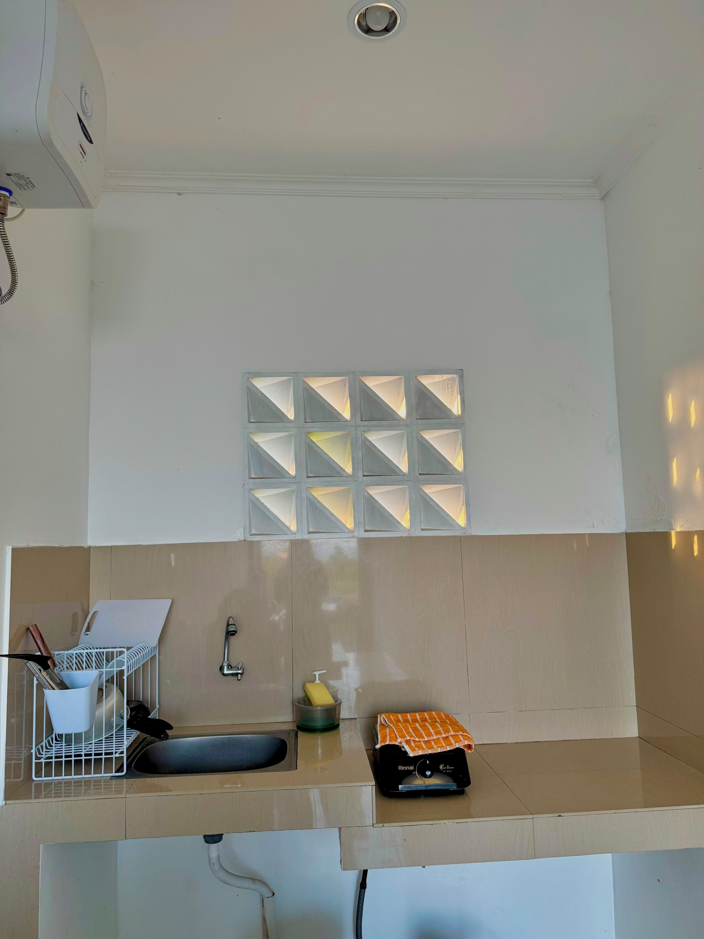 A kitchen with a sink, a whiteboard, and a small window with geometric patterns.