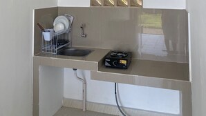 Eine kompakte Küche mit integriertem Geschirrspüler, einer kleinen Spüle und einem kompakten Herd.