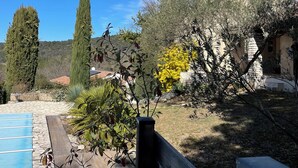 A stone pool with a wooden deck, surrounded by olive trees and a yellow flowering bush. - Uzès, 30 minutes from Mas d'Angel, at Éric & France (Cornillon)