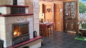 A stone fireplace with a modern design, a wooden dining area with a table and chairs, and a door with decorative metalwork. - Large gîte for 14 people with hot tub & fireplace 🌲 Nature, forest & relaxation (raon sur plaine)
