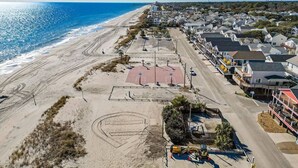 An aerial view of a beachside residential area with houses, a basketball court, and a road leading to the beach. - Branch Breeze - Golf Cart | Linens | Ocean Lakes (Myrtle Beach)