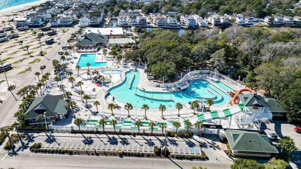 An aerial view of a resort with a large swimming pool, a water slide, and a beach in the background. - Branch Breeze - Golf Cart | Linens | Ocean Lakes (Myrtle Beach)
