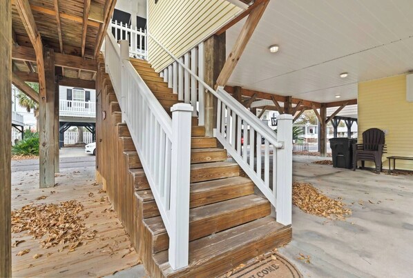 A wooden staircase with white railings leading to a covered porch area.
