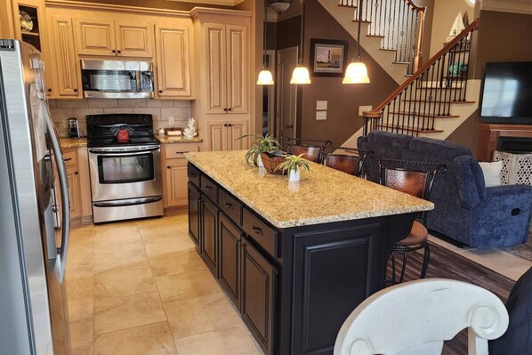 A kitchen with granite countertops, stainless steel appliances, and a central island with plants.