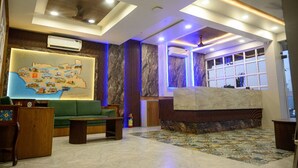 Una hall con un divano verde, un murale con una mappa e una reception.
