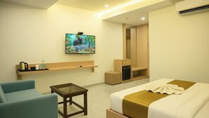 A hotel room with a bed, a desk, a chair, a TV, and a wardrobe.