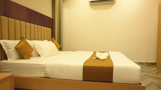 Un letto ben rifatto con un poggiatesta, cuscini e una coperta.
