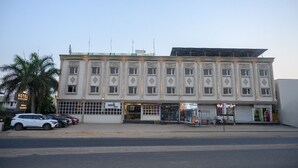 A large, multi-story building with a flat facade, several ground-level shops, and a solar panel on the roof.