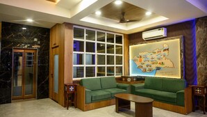 A hotel lobby with a marble floor, wooden furniture, a large window, and a wall-mounted map.