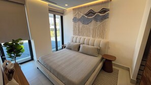 A modern bedroom with a large bed, a decorative wall piece, a small table, and a potted plant.