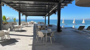 An outdoor patio with tables and chairs, overlooking the sea.