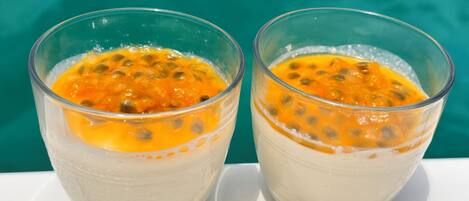 Two glasses of a creamy beverage with a fruit topping, placed on a white surface with a blue background.