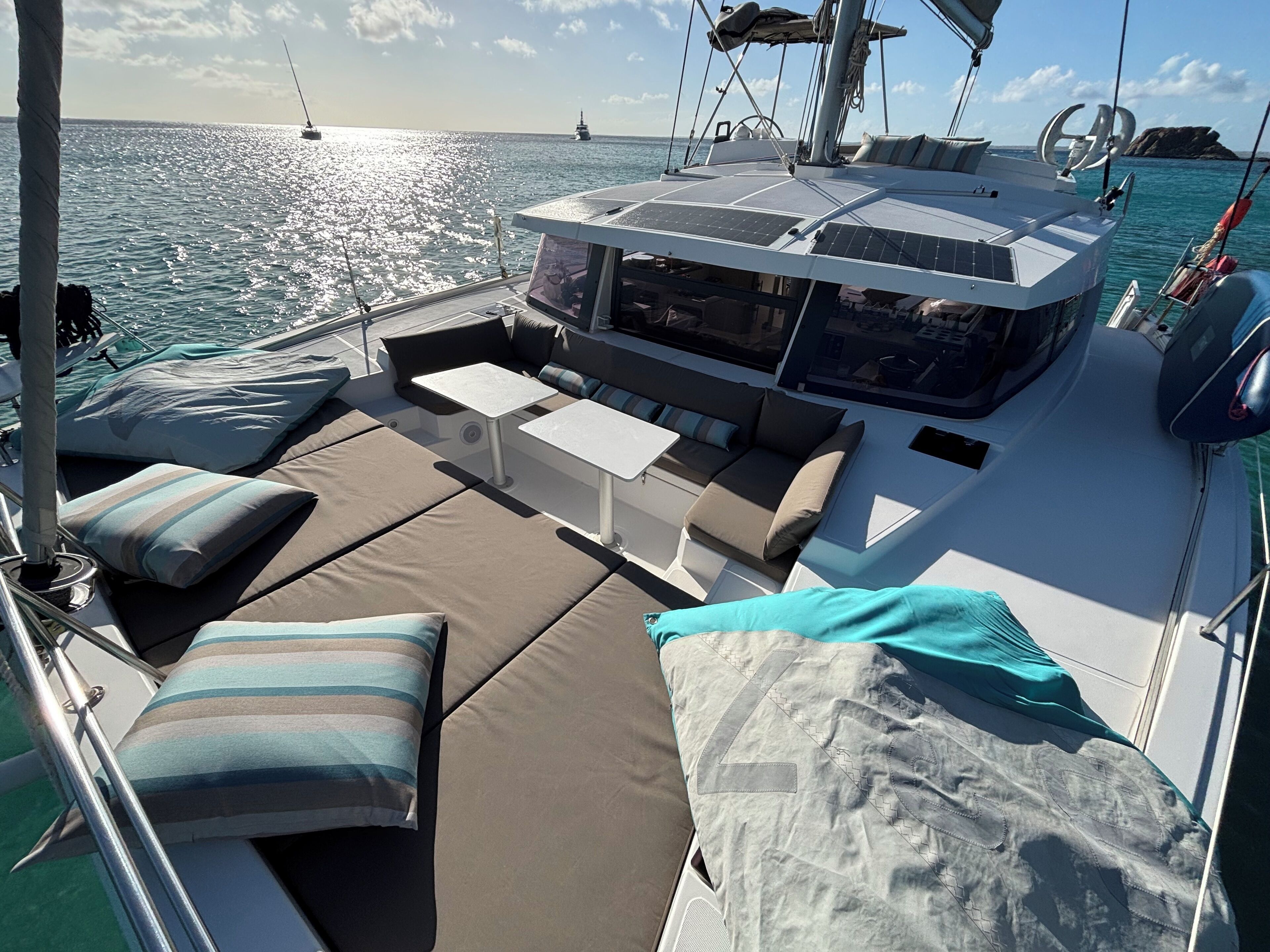 Une terrasse ensoleillée avec des sièges confortables, une petite table et une vue sur l’océan.