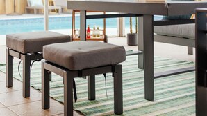 A patio area with a pool, outdoor furniture, and a wooden game table.