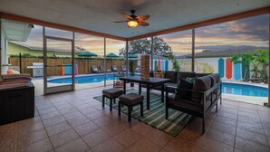 A spacious patio with a pool, outdoor seating, and a view of the sunset.