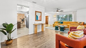 A spacious living room with a large sofa, a coffee table, and a dining area with a wooden table and chairs.