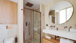 Ein modernes Badezimmer mit Duschkabine aus Glas, einem Holzwaschtisch und einem großen Spiegel.