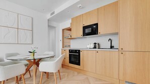 Eine moderne Küche mit Holzausstattung, einer schwarzen Mikrowelle und einem eingebauten Backofen.