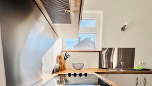 A modern kitchen with a wooden countertop, stainless steel appliances, and a window providing natural light. - Maison proche rivière avec jardin  (Esneux)