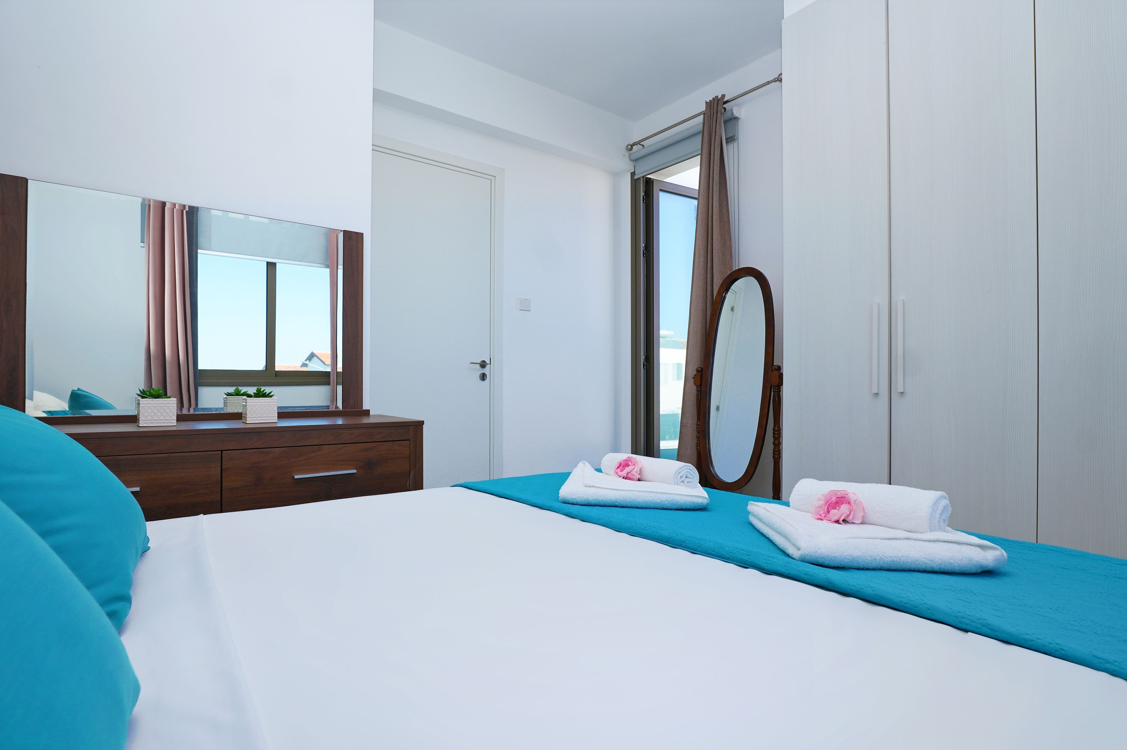 A hotel room with a bed, a dresser, a mirror, and a wardrobe.