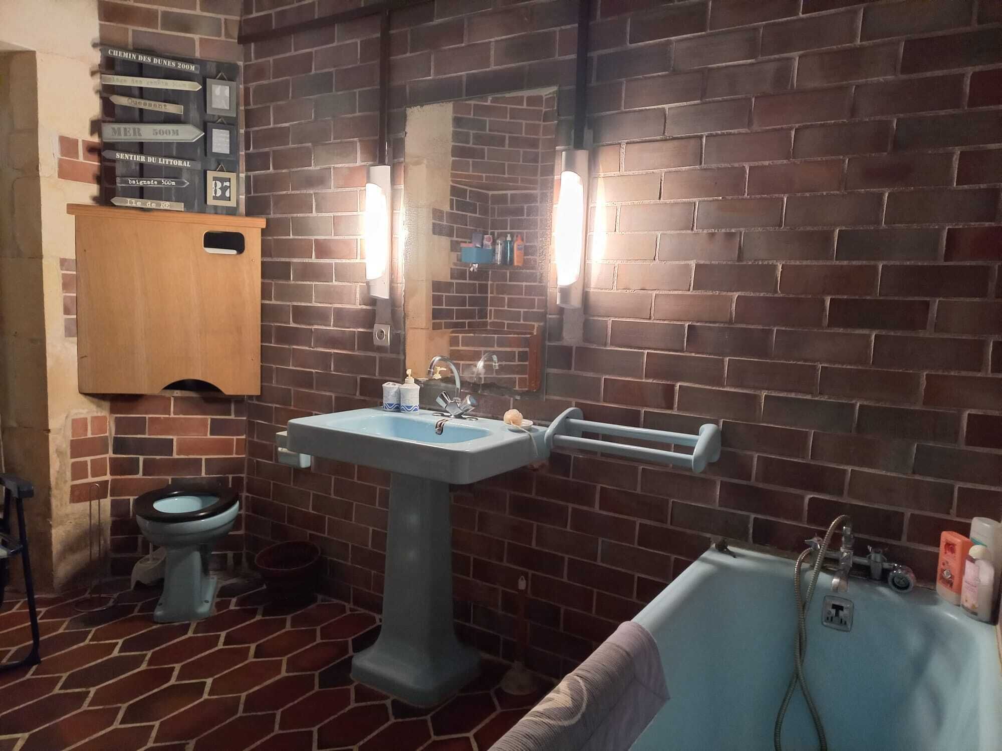 Een badkamer met een bakstenen muur, een wastafel, toilet en een bad.