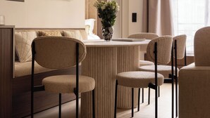 Una sala de estar moderna con un sofá, sillas, una mesa de centro y un jarrón con flores.