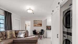 A modern living room with a sectional sofa, a dining area, and a built-in washer and dryer. - Bright and Cozy Home in Homestead (Homestead)