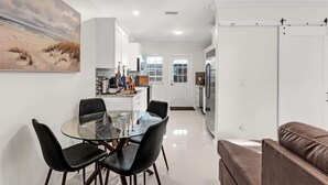 A modern kitchen with white cabinets, a glass dining table, and black chairs. - Bright and Cozy Home in Homestead (Homestead)