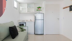 A compact living space with a kitchenette, a refrigerator, a sofa, and a door. - MOT Libertador 5700 (Buenos Aires)