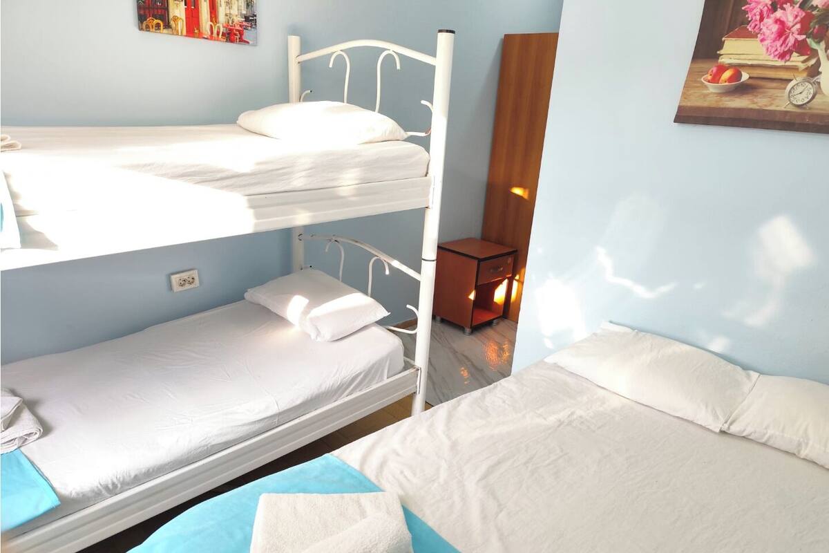 Dormitorio con literas, una mesita de noche pequeña y una mesita auxiliar.