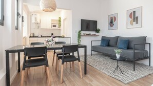 A modern living room with a grey sofa, black chairs, a glass dining table, and a kitchen in the background. - MOT Libertador 6300 (Buenos Aires)