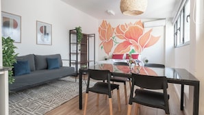 A modern living room with a sofa, a dining table with chairs, a large floral mural, and a hanging light fixture. - MOT Libertador 6300 (Buenos Aires)