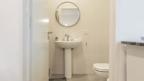 A small, clean bathroom with a white sink, a round mirror, and a toilet. - MOT Libertador 6300 (Buenos Aires)