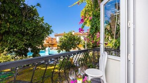 A balcony with a view of a swimming pool, a table with a bottle and glasses, and a chair. - Legend Of Dalyan Hotel (Ortaca)