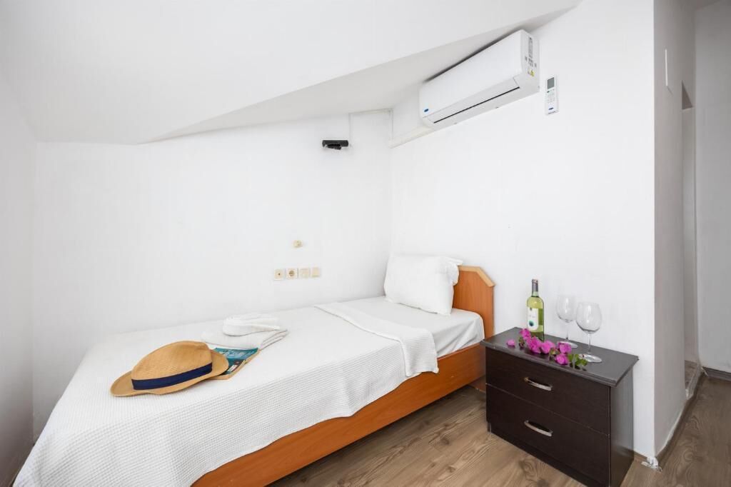 Une petite chambre à coucher, bien rangée, avec un lit simple, une table de chevet et une commode.