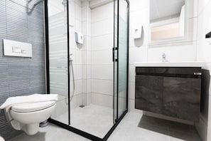 A modern bathroom with a toilet, a glass-enclosed shower, and a vanity with a sink.