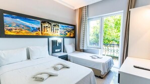 A hotel room with two beds, a desk, a nightstand, and a large window with a view of greenery. - Legend Of Dalyan Hotel (Ortaca)