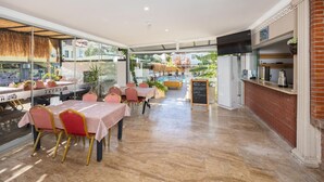 A restaurant with indoor seating, a pool in the background, and a chalkboard menu. - Legend Of Dalyan Hotel (Ortaca)