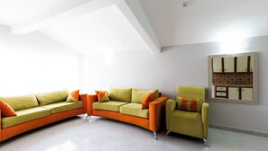 A modern living room with a curved sofa set, a single armchair, and a built-in kitchen cabinet. - Legend Of Dalyan Hotel (Ortaca)