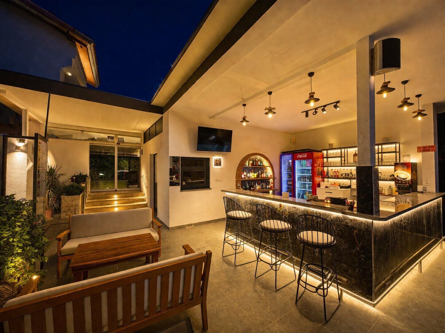 A modern kitchen with a bar area, bar stools, and a television.