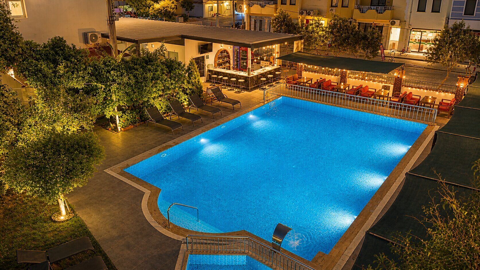 A swimming pool with a bar area, lounge chairs, and a covered seating area.