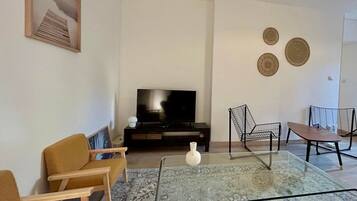 A living room with a sofa, a glass coffee table, a TV, and two chairs.