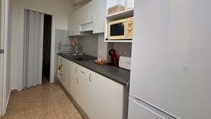 A compact kitchen with white cabinets, a microwave, a toaster, and a refrigerator. - Cervantes Apartment (Villena)
