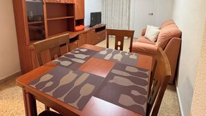 A compact living space with a dining table, chairs, a sofa, and a wooden cabinet. - Cervantes Apartment (Villena)