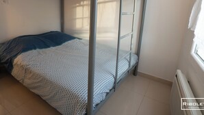 Un letto a castello con copriletto decorato, un cuscino e una finestra con tende.