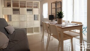 Un soggiorno moderno con un divano, un tavolo da pranzo, sedie, una TV e un armadio a muro.