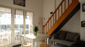 A dining area with a table and chairs, a staircase, and a sofa.