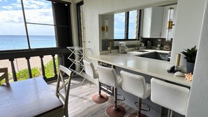 A modern kitchen with a large island, bar stools, and a view of the ocean. - Leisure Daze by the Sea (Frederiksted)